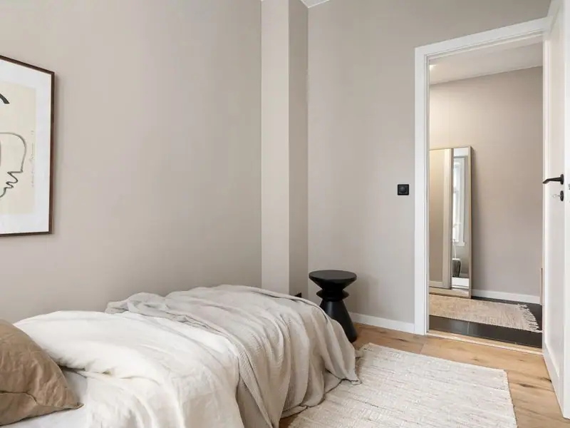 A simple room with a single bed and soft morning light