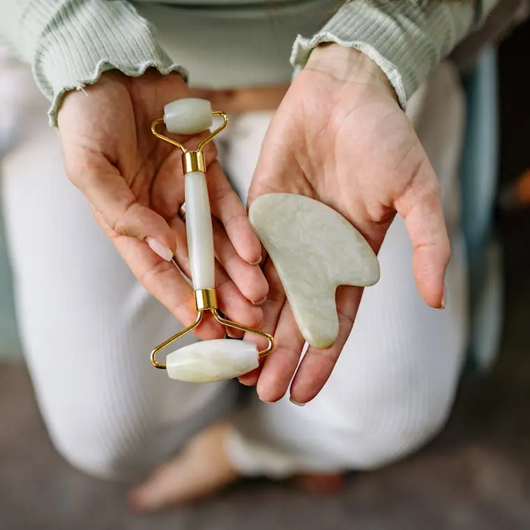 A close-up of a gua sha and face roller skincare ritual